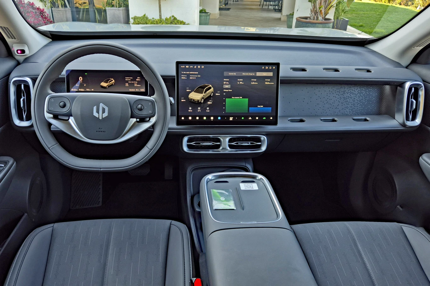 nowoczesna deska rozdzielcza elektrycznego samochodu z dużym ekranem dotykowym pośrodku, cyfrowym wyświetlaczem za kierownicą, minimalistycznym wykończeniem i ergonomicznymi fotelami kierowcy oraz pasażera