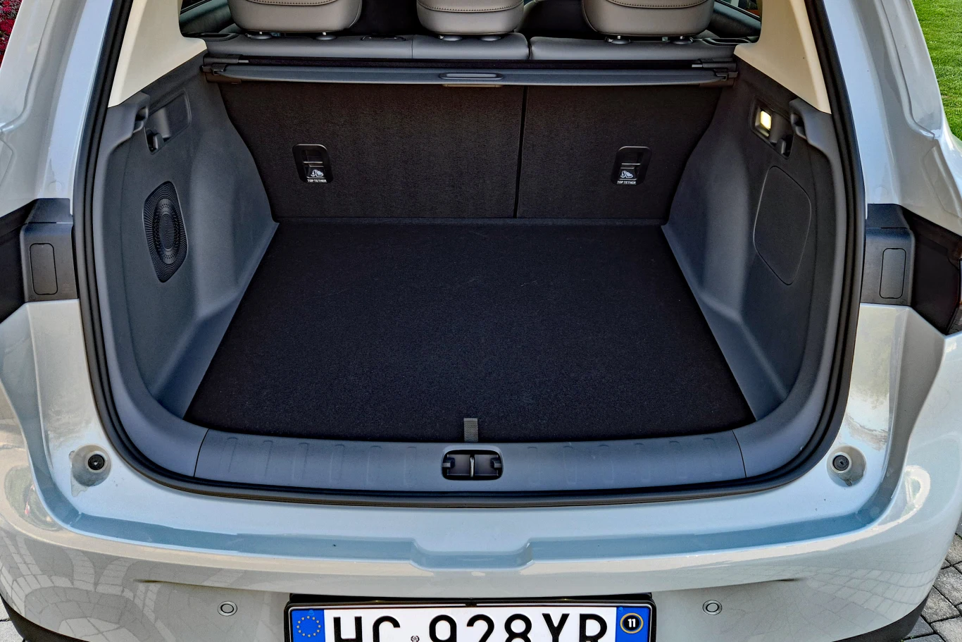 pojemny bagażnik samochodu o płaskim dnie, wykończony ciemną tapicerką, z widocznymi zagłówkami tylnej kanapy i otwartą klapą bagażnika