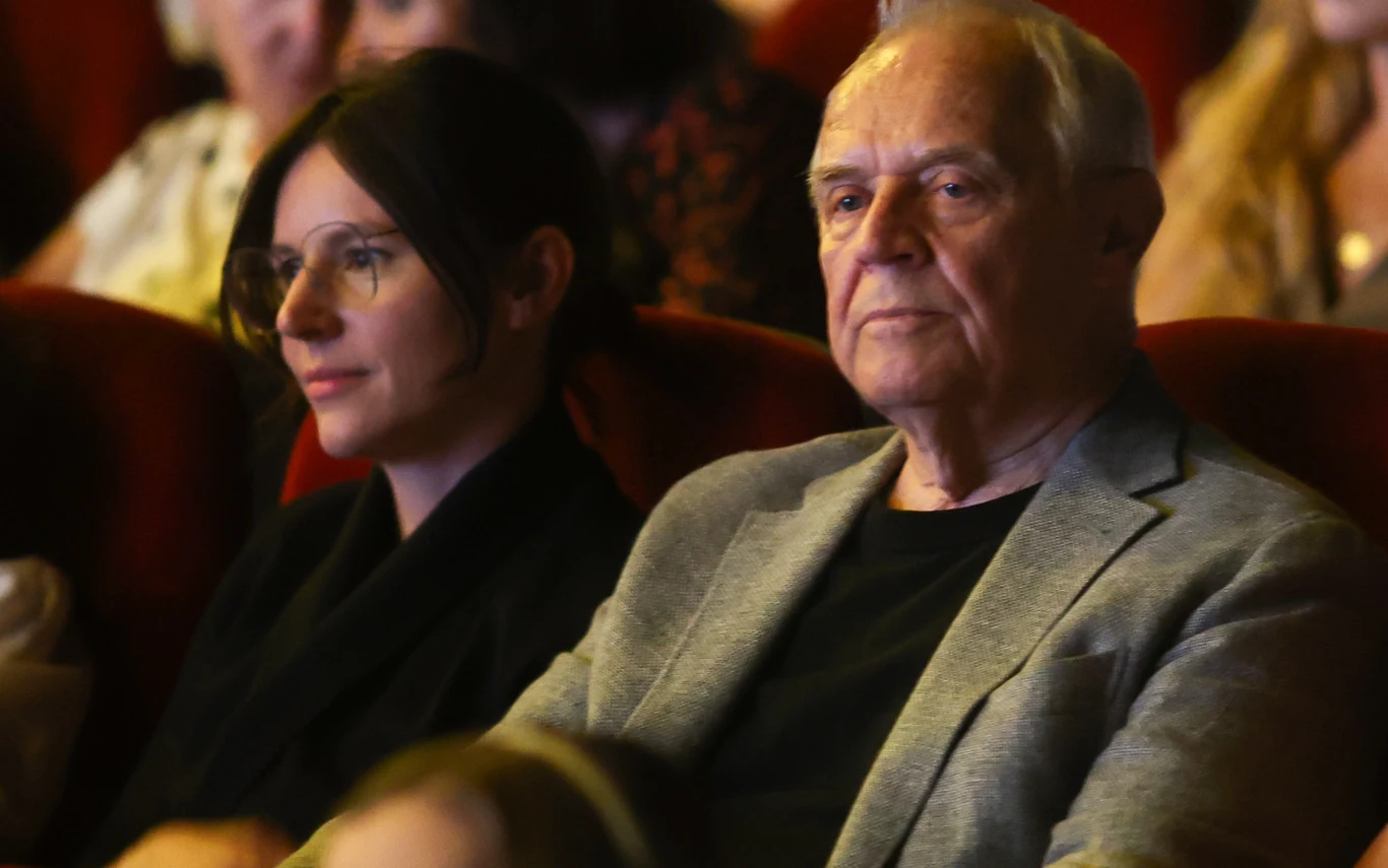 Marek Kondrat z żoną Antoniną Turnau Marek Kondrat w szarej marynarce i Antonina Turnau w okularach na czerwonych fotelach podczas wydarzenia.