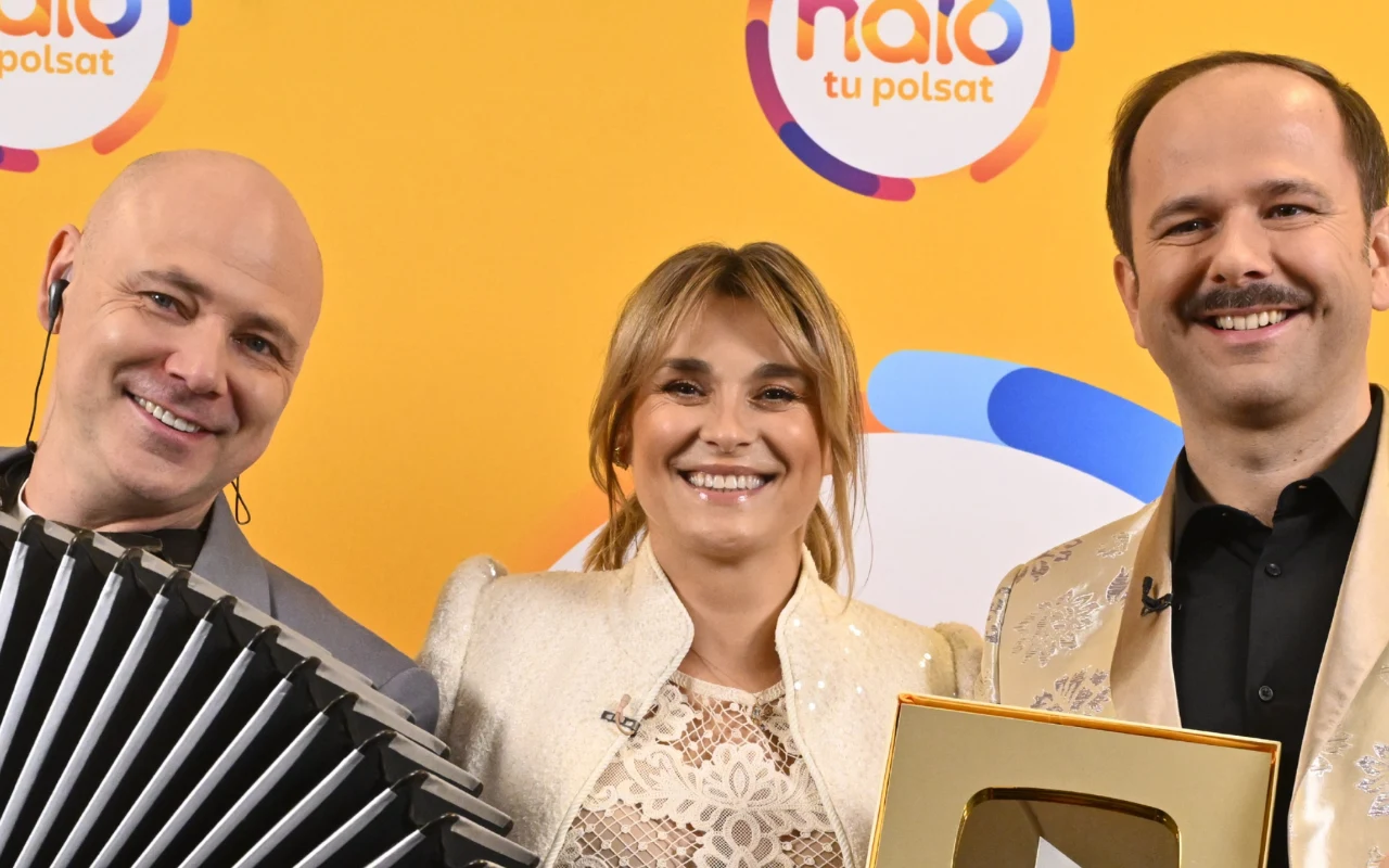 Marcin Wyrostek, Kajra i Sławomir w "halo tu polsat" troje uśmiechniętych osób na tle żółtej ścianki z logo, jedna trzyma akordeon, druga złotą statuetkę z symbolem YouTube, wszyscy ubrani elegancko w jasne stroje