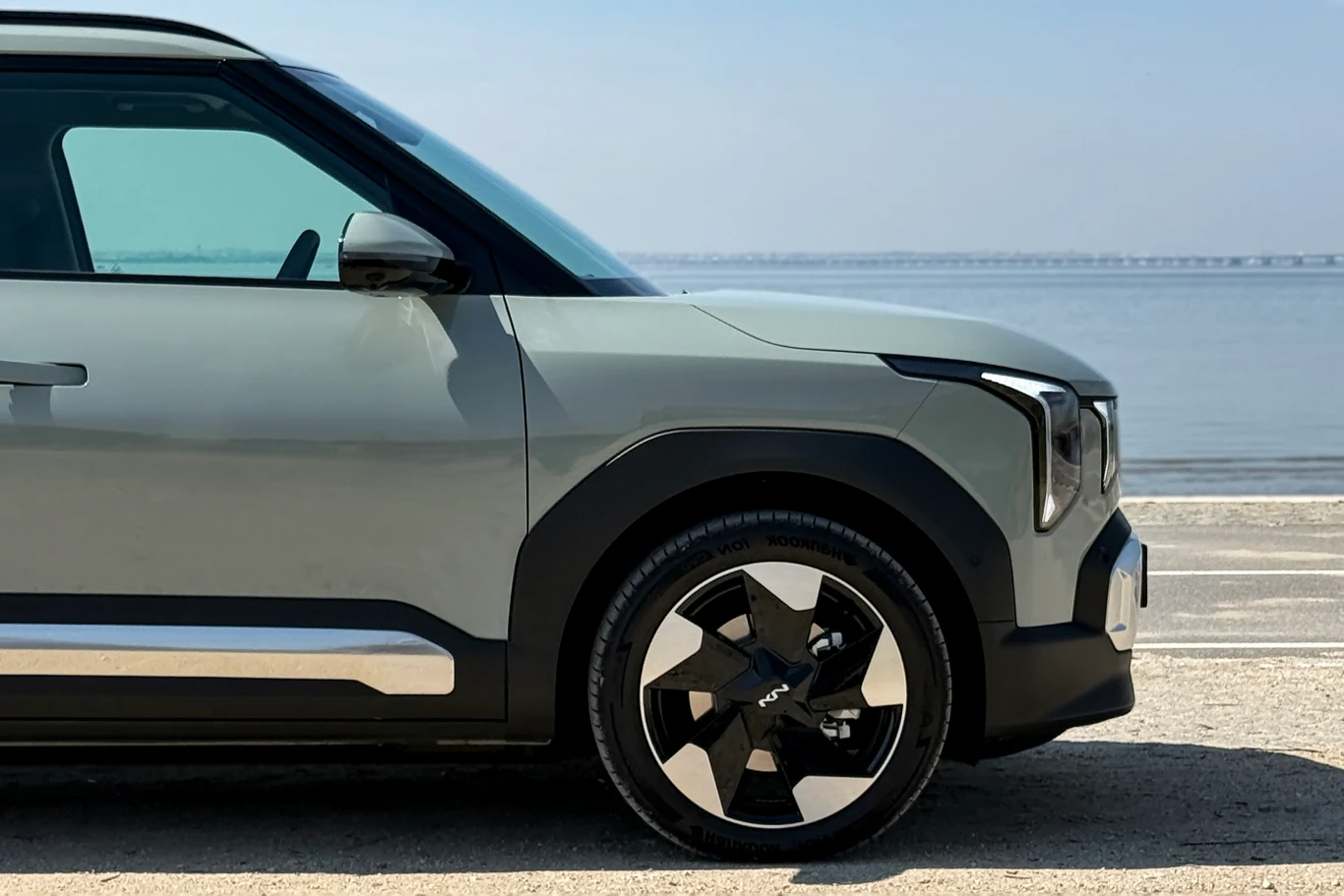 nowoczesny samochód typu SUV zaparkowany nad brzegiem wody, widoczny przedni fragment auta z charakterystycznym reflektorem i efektowną aluminiową felgą