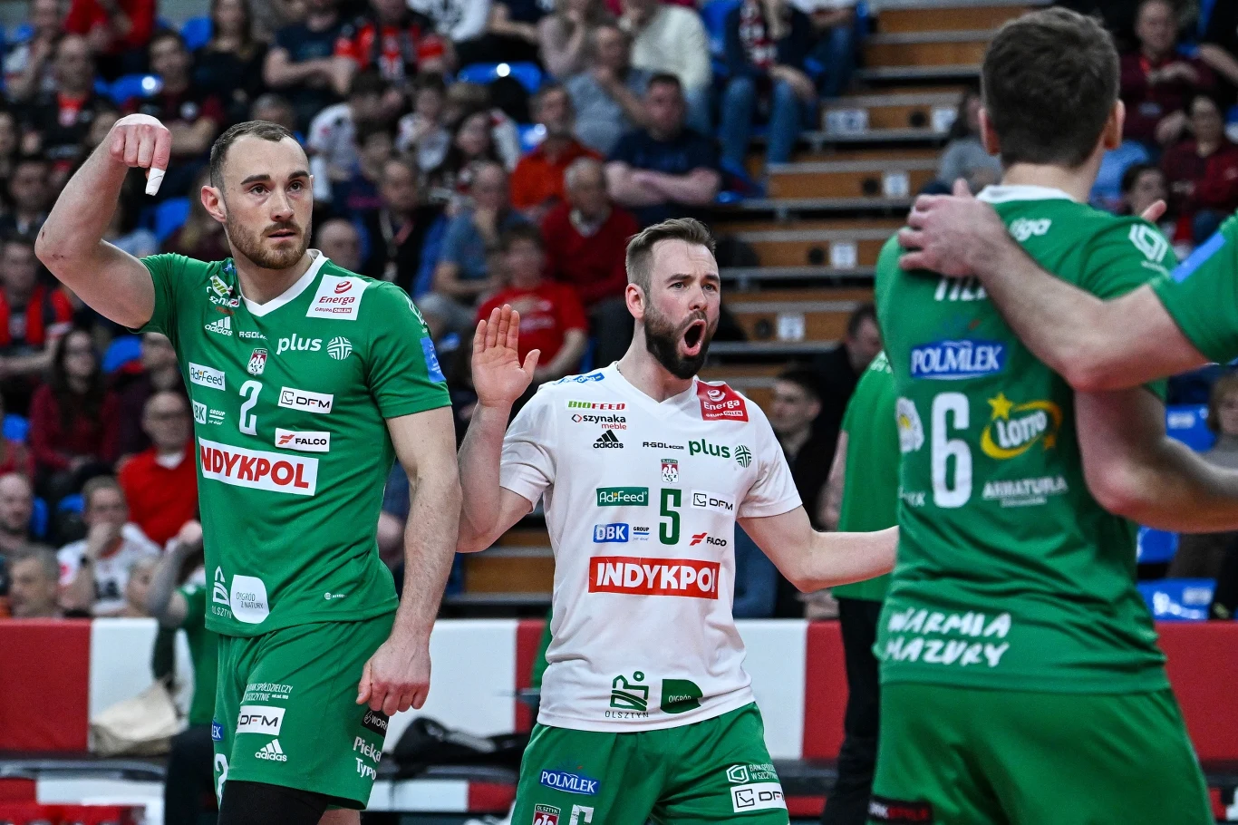 siatkarze drużyny Indykpol AZS Olsztyn w zielonych i białych strojach celebrują punkt, jeden z zawodników głośno wyraża emocje, na trybunach widoczna publiczność