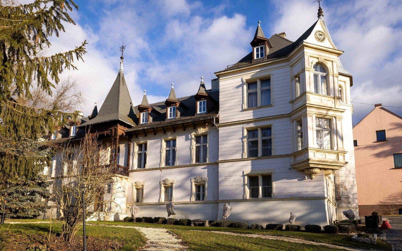 Pałac w Ławicy Widok na zabytkowy Pałac w Ławicy z eklektyczną fasadą. Budynek o białych ścianach z wieżyczkami i strzelistymi hełmami.