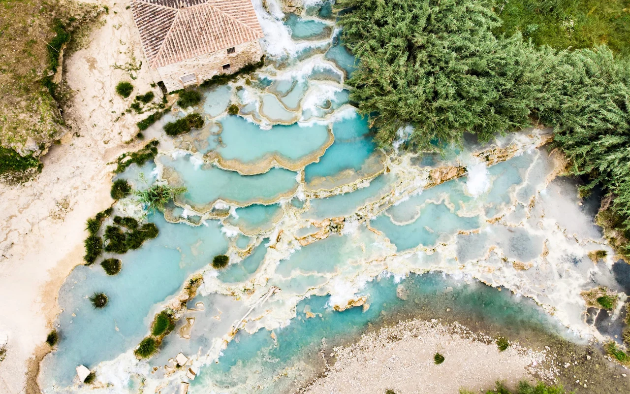 To jedno z najpiękniejszych miejsc w Europie Kaskadowe baseny termalne o turkusowej wodzie otoczone naturalną roślinnością oraz starym budynkiem z dachówką, widoczne z lotu ptaka.