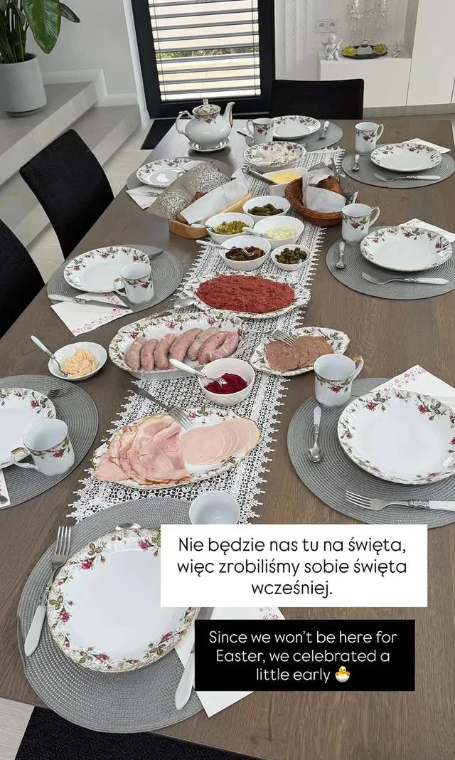 Stół zastawiony elegancką porcelaną i świątecznym obrusem, w centralnej części ułożone półmiski z wędlinami, serami, jajkami oraz różnymi pastami i dodatkami, dookoła talerze z ułożonymi sztućcami i filiżankami, tworząc odświętną atmosferę rodzinnego ś...
