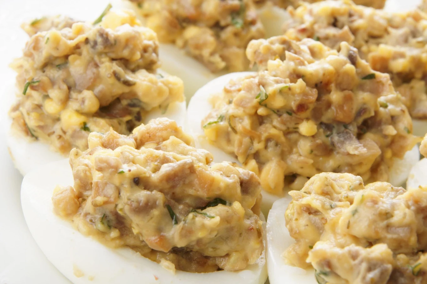 Jajka faszerowane z karmelizowaną cebulką to dobry pomysł na wielkanocne śniadanie Połówki jajek faszerowane karmelizowaną cebulką, pieczarkami i żółtkiem, ułożone na talerzu.