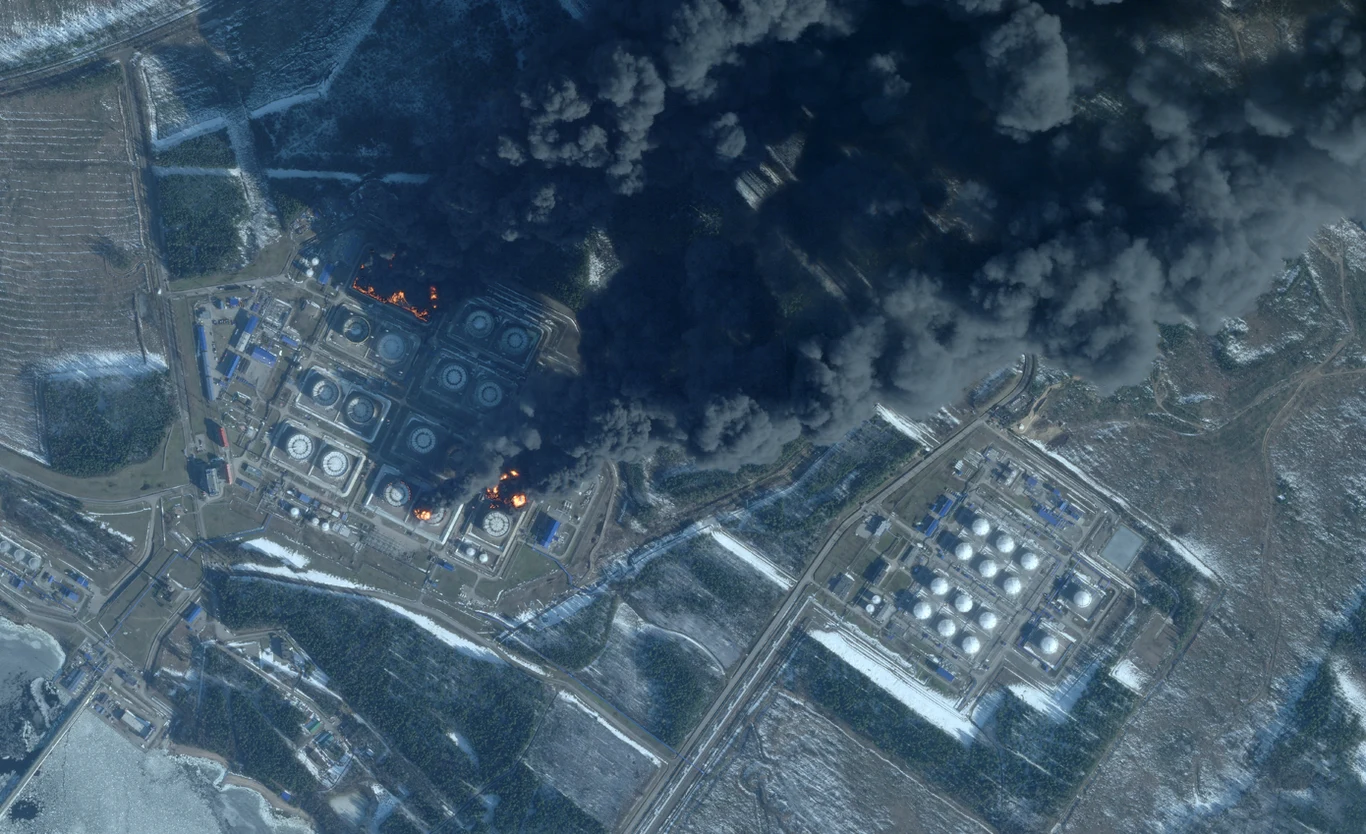 Zdjęcie satelitarne z ataku na Primorsk 23 marca Duże zbiorniki na paliwo otoczone płomieniami i gęstym, ciemnym dymem unoszącym się nad kompleksem przemysłowym wśród zaśnieżonego krajobrazu.