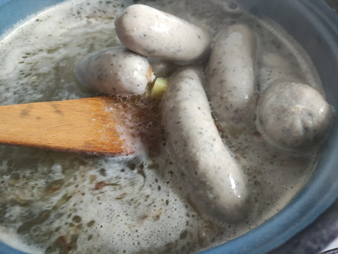 biała kiełbasa gotowana w wodzie z dodatkiem przypraw, mieszana drewnianą łopatką