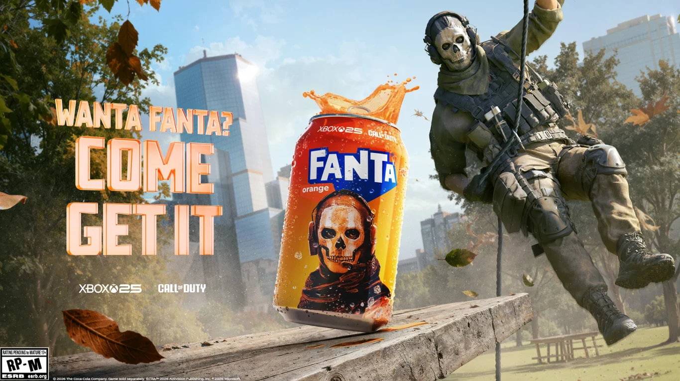 puszka Fanta z pomarańczowym napojem i nadrukiem czaszki na tle miasta, po prawej stronie postać w wojskowym stroju i masce z czaszką zjeżdża na linie, obok duży napis reklamowy zachęcający do zakupu Fanty