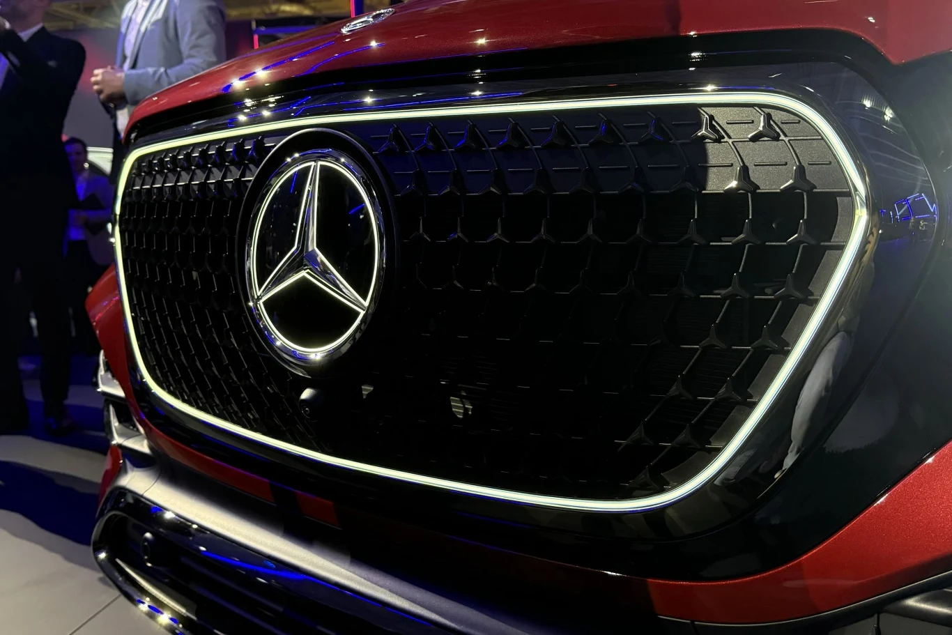 duży grill z wyraźnym podświetlanym logo Mercedesa na tle ciemnoczerwonego nadwozia