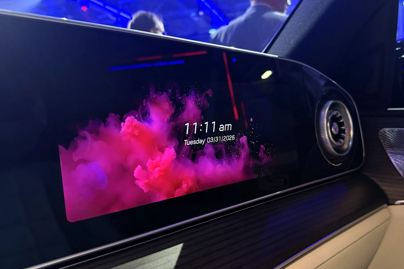 nowoczesny ekran multimedialny w samochodzie z kolorową grafiką różowo-fioletowego dymu, wyświetlający godzinę 11:11 oraz datę wtorek, 31 marca 2026; po prawej stronie widoczny okrągły nawiew wentylacyjny z metalowym wykończeniem