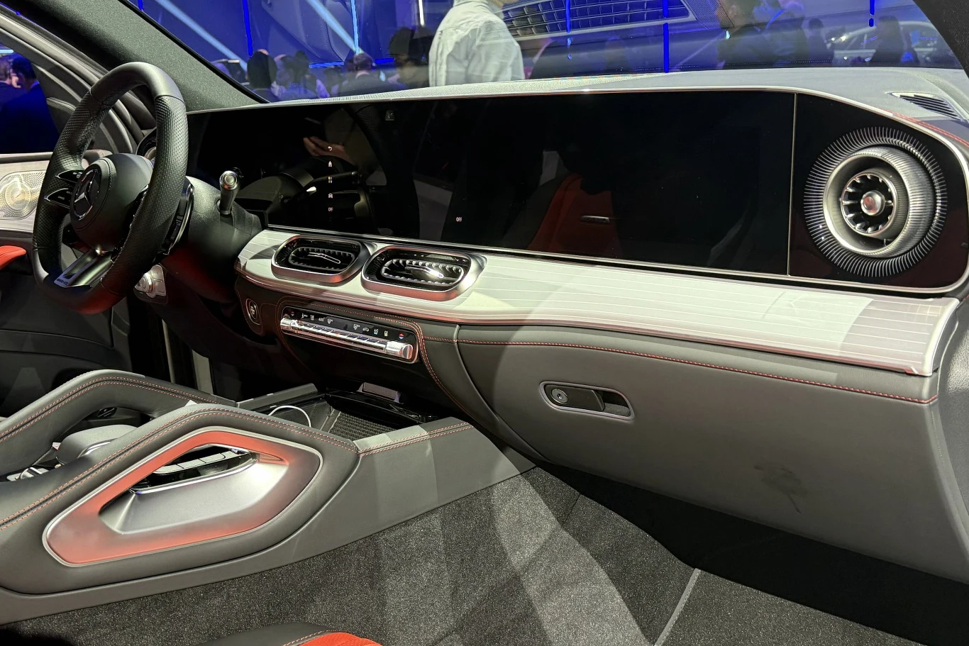 nowoczesne wnętrze samochodu z dużym, zakrzywionym ekranem dotykowym na desce rozdzielczej, eleganckim wykończeniem oraz charakterystycznymi nawiewami wentylacyjnymi o futurystycznym wyglądzie