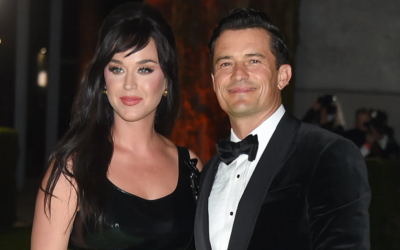 Kobieta w długiej, czarnej sukni oraz mężczyzna w czarnym smokingu stoją razem uśmiechnięci na eleganckim wydarzeniu wieczorowym.