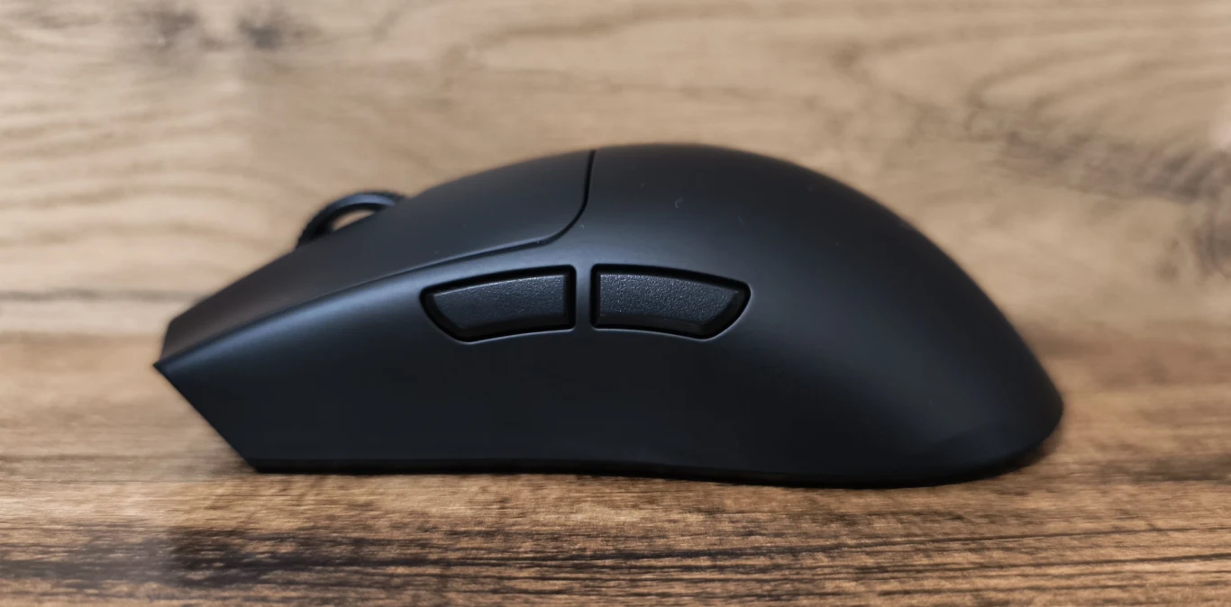 czarna mysz komputerowa z dwoma bocznymi przyciskami umieszczona na drewnianym blacie, na tle jasnego drewna