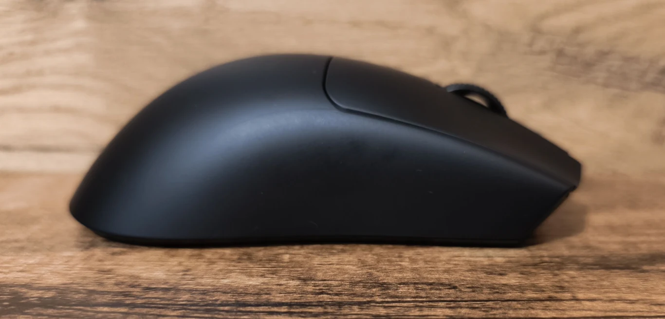 czarna mysz komputerowa o ergonomicznej, opływowej konstrukcji ustawiona na drewnianej powierzchni, sfotografowana z profilu