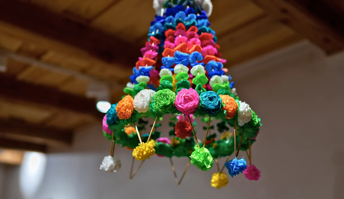 tradycyjna ozdoba wykonana z kolorowych, bibułowych kwiatów tworzących stożkową formę, zawieszona pod drewnianym sufitem