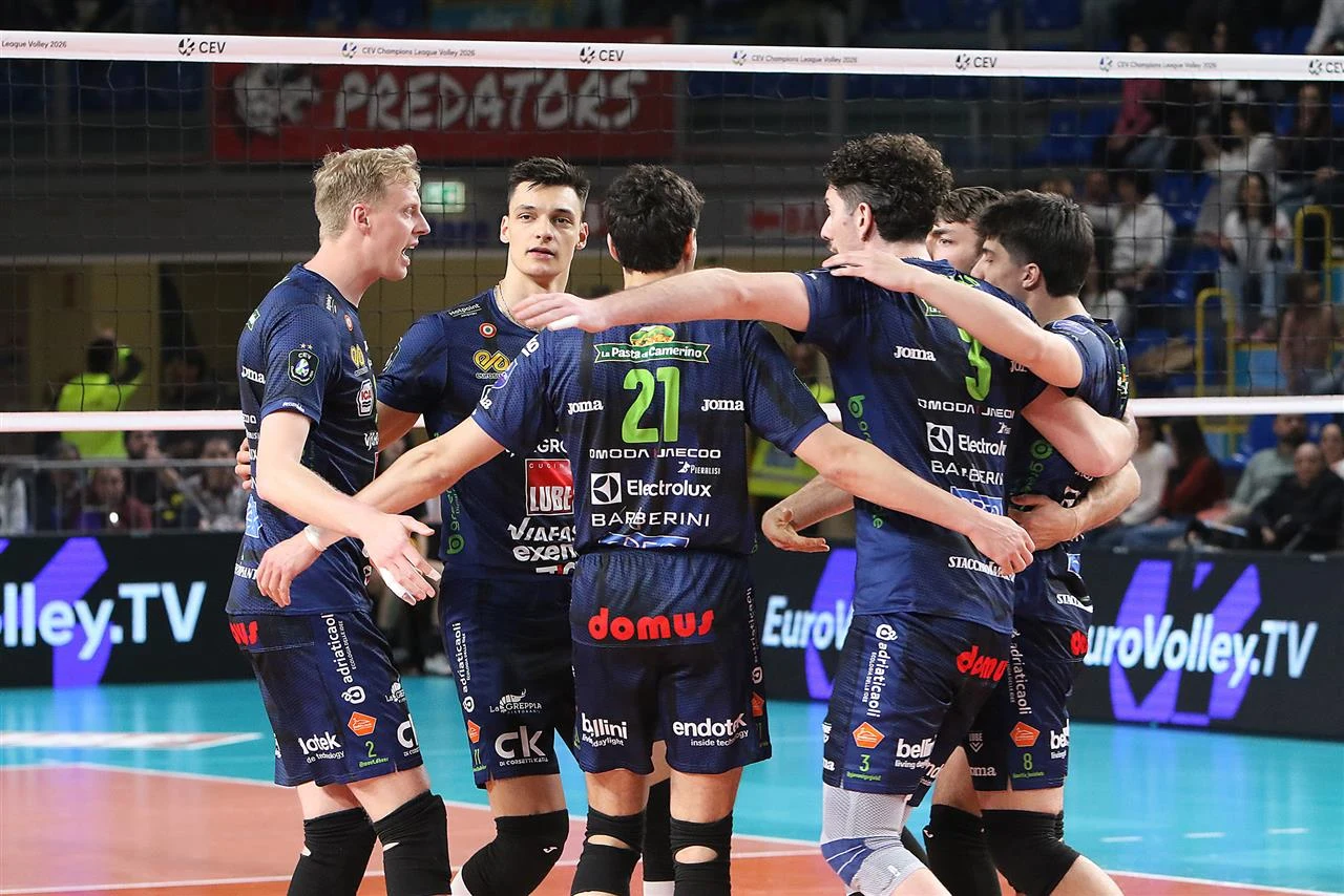 grupa siatkarzy w niebieskich strojach świętuje zdobycie punktu, obejmując się i tworząc krąg na boisku podczas meczu