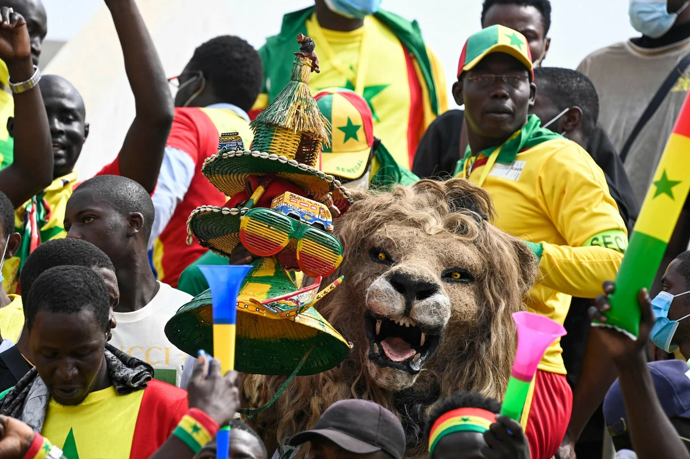 Kibice reprezentacji Senegalu, czyli "lwów Terangi" tłum kibiców ubranych w żółto-zielone barwy z flagami Senegalu, maskotka lwa z otwartą paszczą na pierwszym planie oraz tradycyjne afrykańskie ozdoby i instrumenty