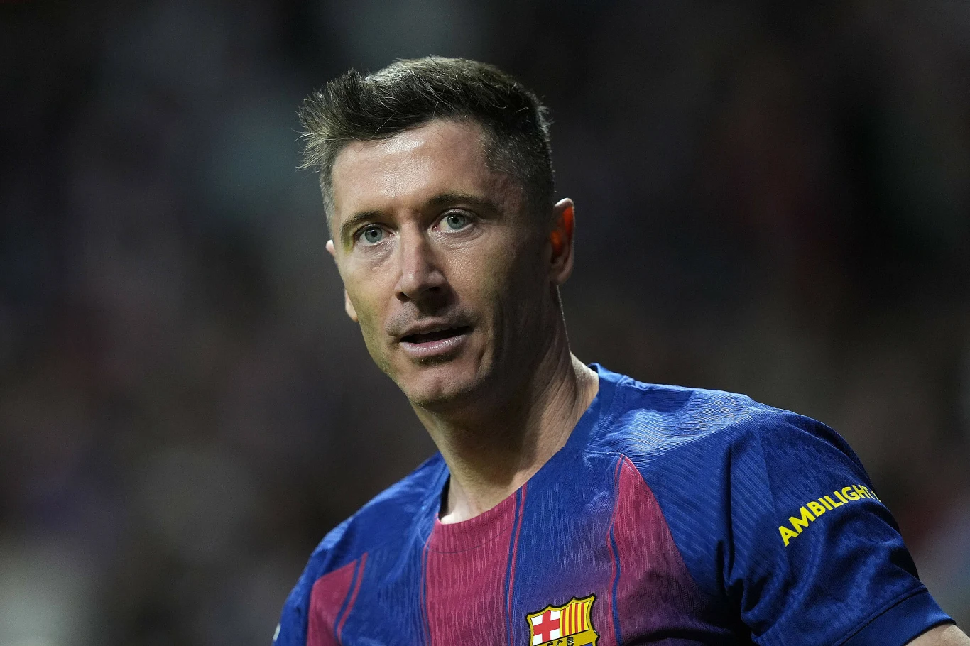 piłkarz w granatowo-bordowej koszulce FC Barcelony stoi na boisku podczas meczu, z wyraźnym skupieniem na twarzy, w tle rozmyte trybuny