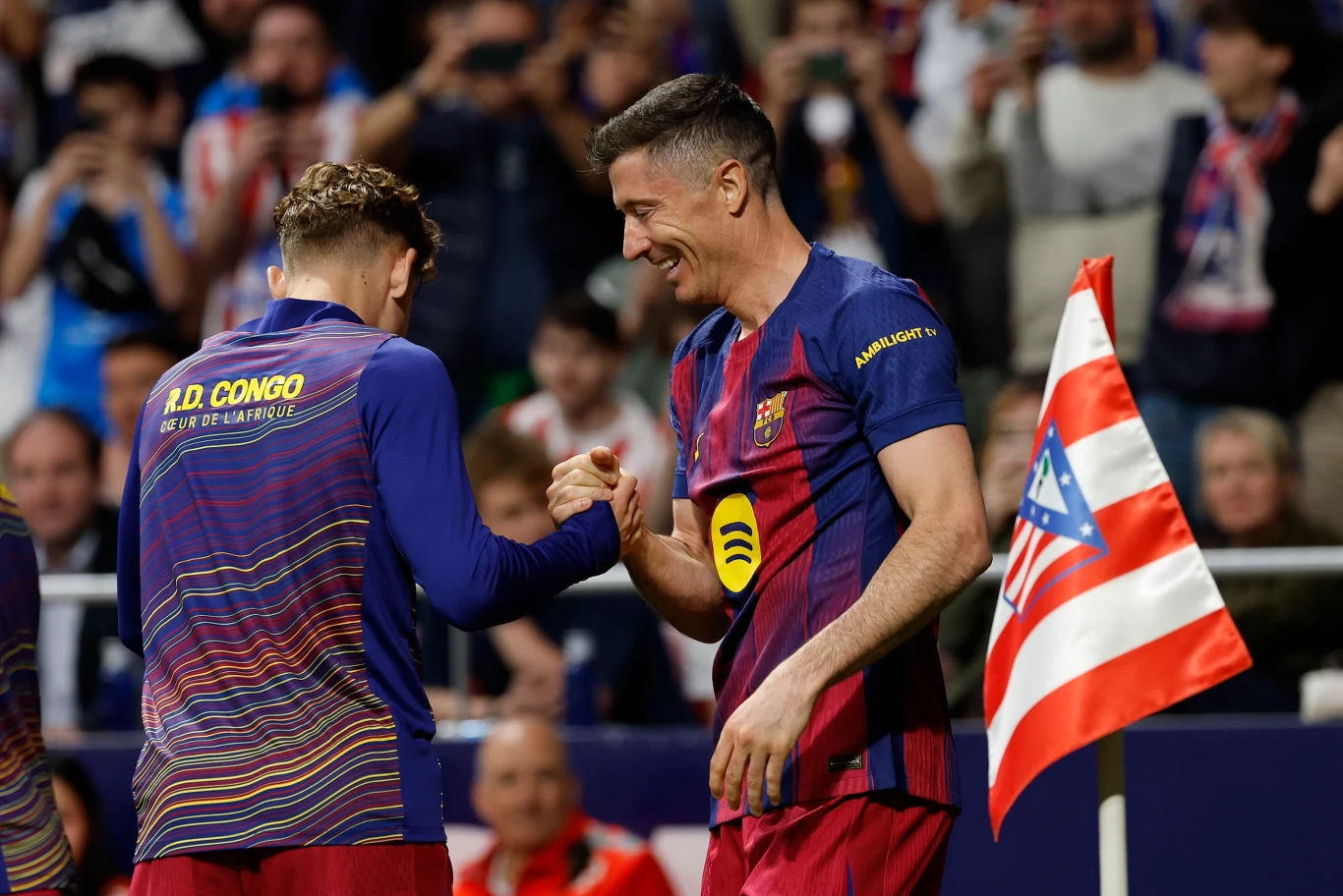 dwóch piłkarzy drużyny FC Barcelony w granatowo-bordowych strojach świętuje udaną akcję przy chorągiewce narożnej na tle kibiców na trybunach