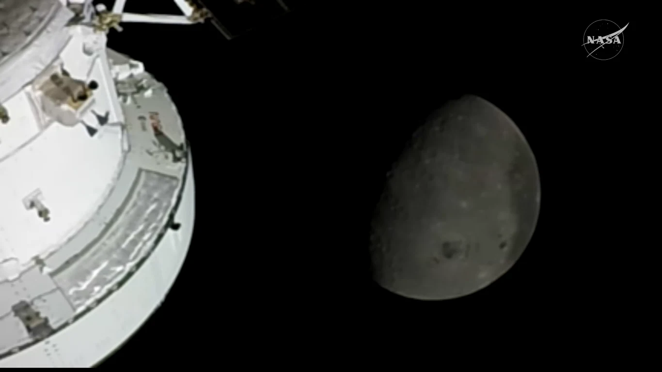 fragment modułu kosmicznego na tle półksiężyca z wyraźnymi szczegółami powierzchni Księżyca oraz głęboką czernią kosmosu w tle