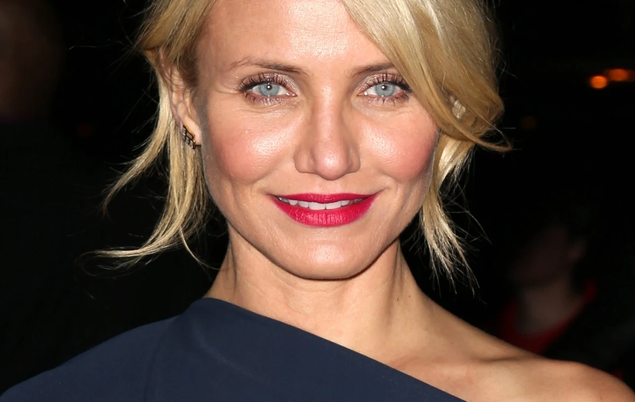 Cameron Diaz Cameron Diaz z jasnymi, spiętymi włosami, czerwonymi ustami i w ciemnej kreacji na jednym ramieniu.
