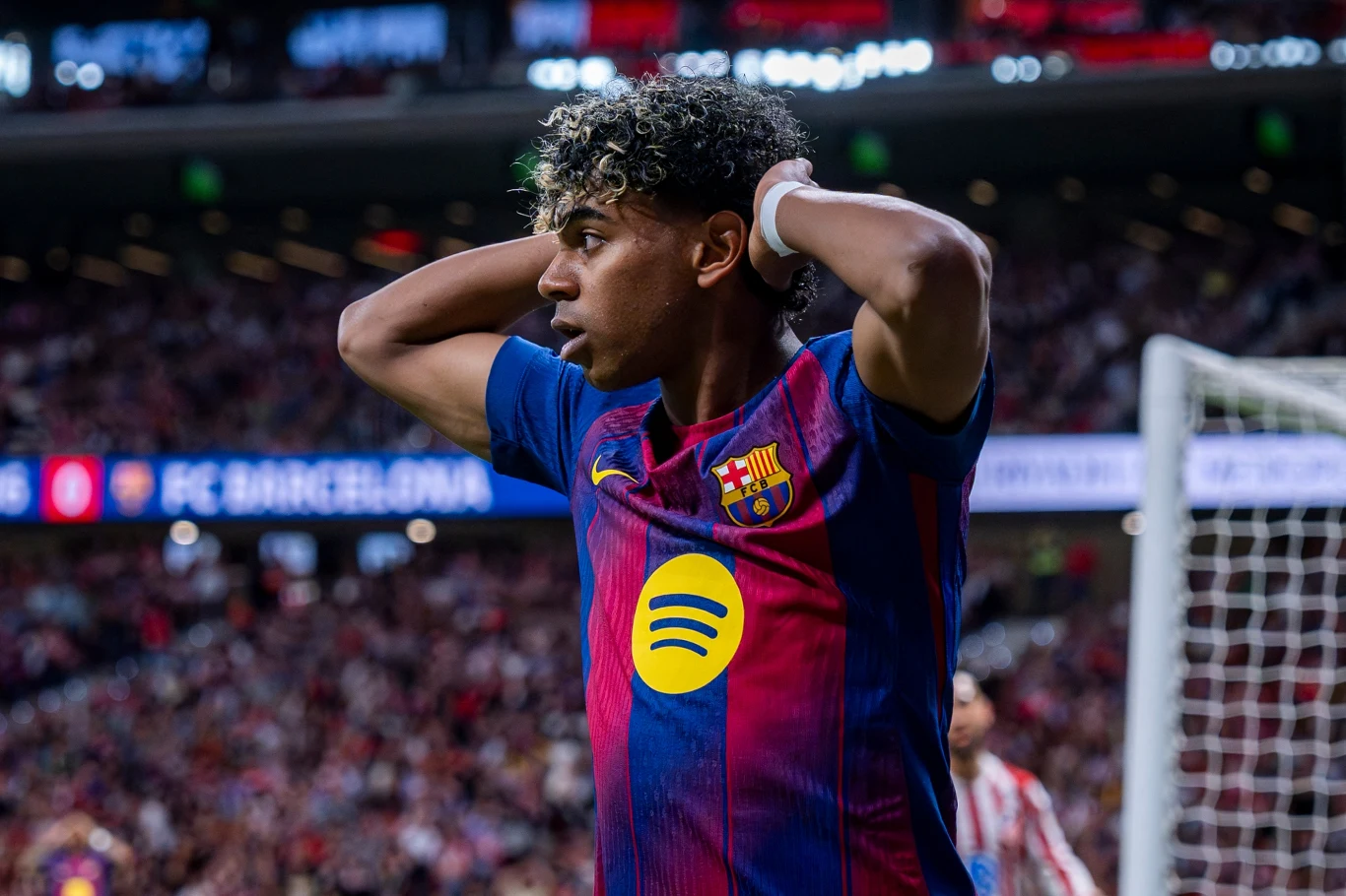 piłkarz FC Barcelony w koszulce klubowej z widocznym logo sponsora trzyma ręce za głową, wyrażając napięcie lub rozczarowanie, w tle rozmazana publiczność stadionu