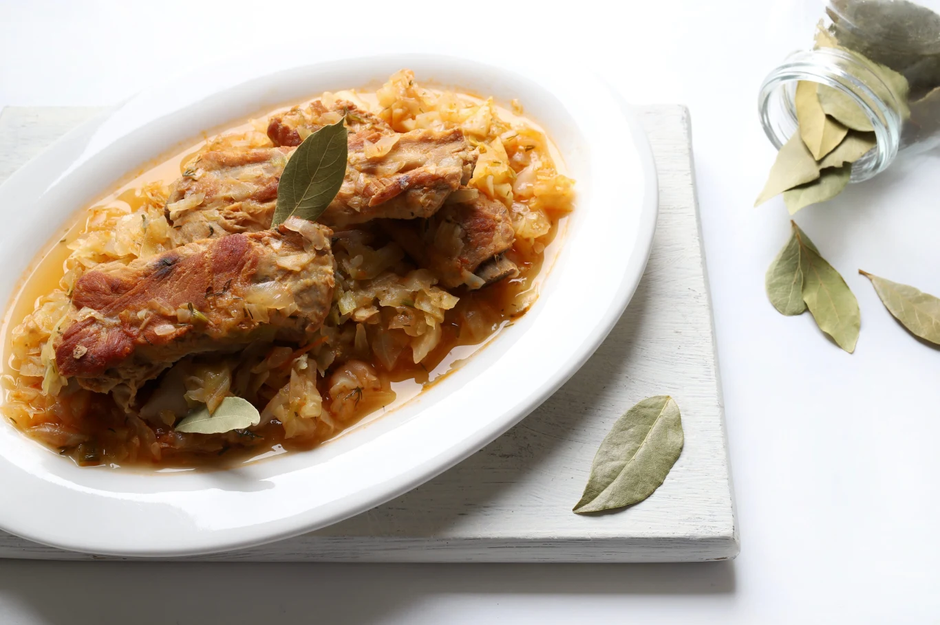 Żeberka z tego przepisu są dobrze przyprawione, aromatyczne i soczyste Żeberka pieczone w kapuście kiszonej na białym półmisku.