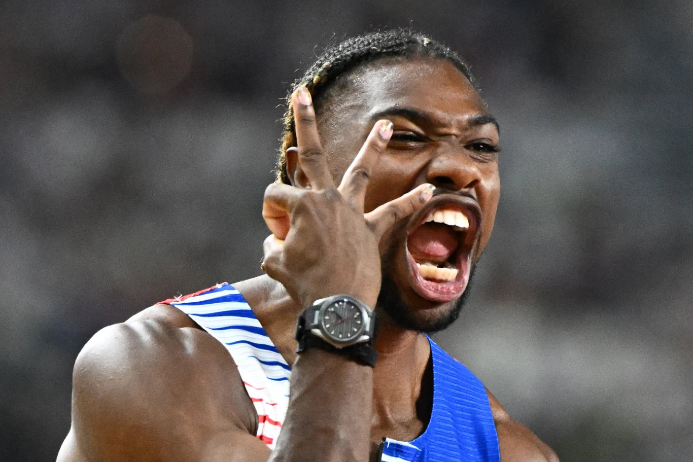 Sportowiec w stroju lekkoatletycznym z dynamicznym wyrazem twarzy wykonuje energiczny gest ręką z szeroko otwartymi ustami, podkreślając emocje i zaangażowanie podczas zawodów.