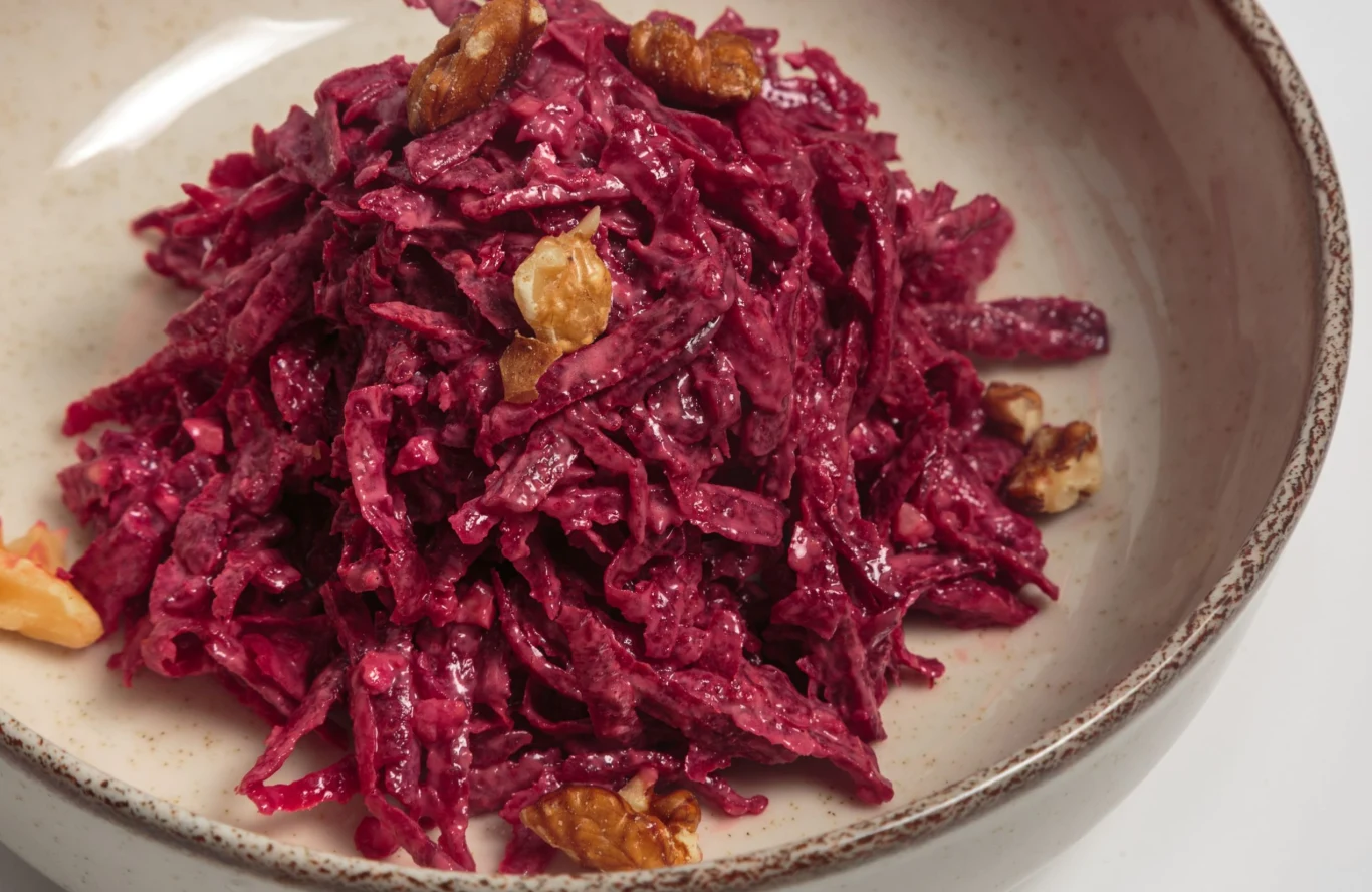 Sałatka z kiszonych buraków to świetnie wsparcie dla zdrowia Sałatka z kiszonych buraków z orzechami włoskimi na jasnym talerzu.