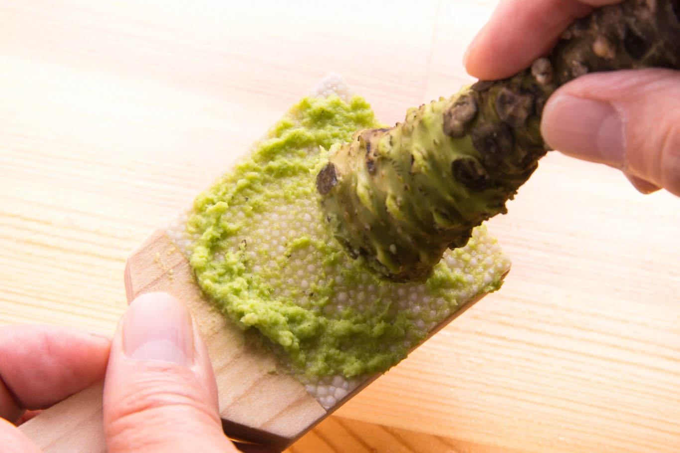 świeżo tarte wasabi na specjalnej tarce, trzymane i ścierane ręką, intensywnie zielona pasta na powierzchni deseczki