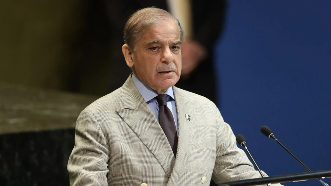 Premier Pakistanu w beżowej marynarce, z brązowym krawatem przemawia przed mikrofonami