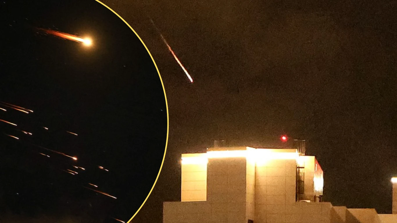 Rakiety na tle ciemnego, nocnego nieba lecące w stronę budynku