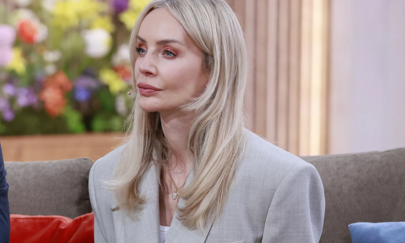 Agnieszka Woźniak-Starak Agnieszka Woźniak-Starak w jasnej marynarce, siedzi na kanapie, w tle rozmyte kolorowe kwiaty