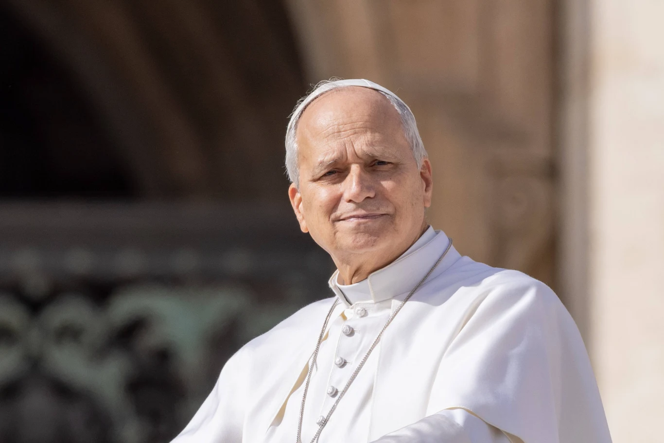 Papież Leon XIV wzywa do wspólnej modlitwy o pokój. Papież Leon XIV stoi przed jasnym rozmytym tłem architektury Watykanu