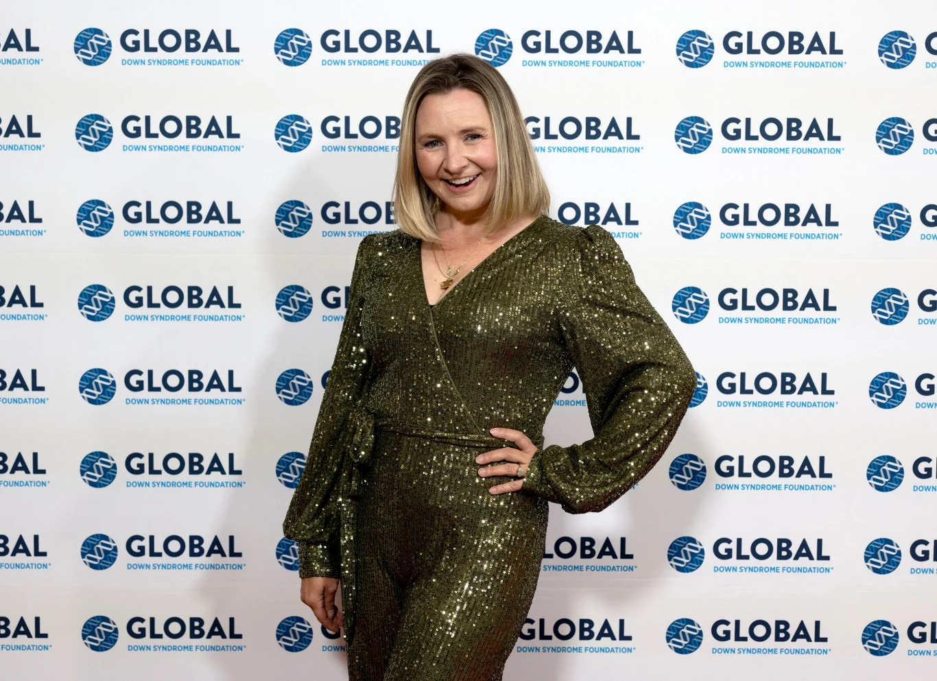 Tak na przestrzeni lat zmieniła się Beverley Mitchell. Dziś aktorka ma 45 lat Kobieta w połyskującej, oliwkowej sukni z długimi rękawami pozuje z uśmiechem na ściance z logo Global Down Syndrome Foundation.
