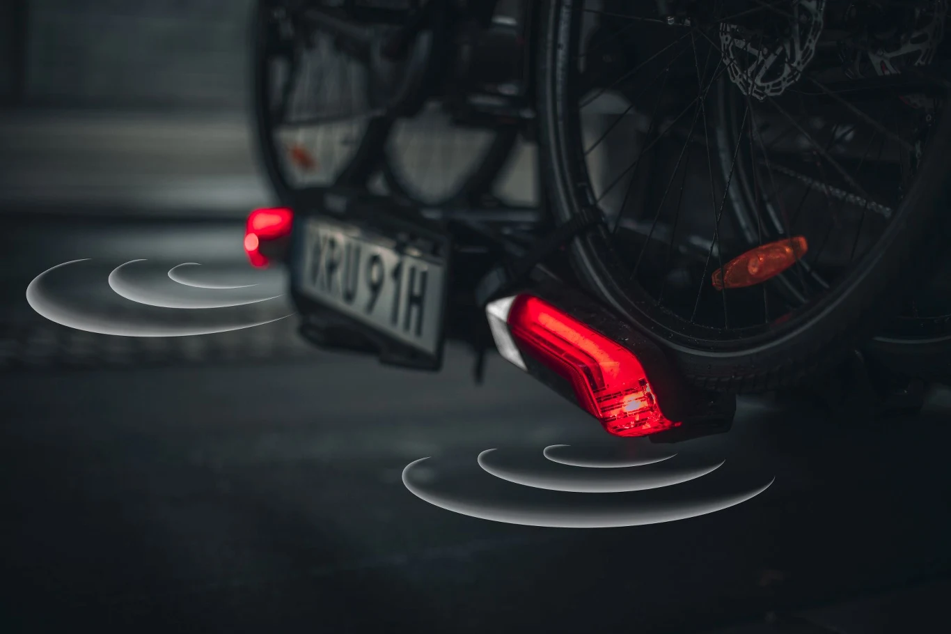 rower zamontowany na bagażniku samochodowym z aktywnymi tylnymi światłami oraz sygnalizacją działania czujników parkingowych