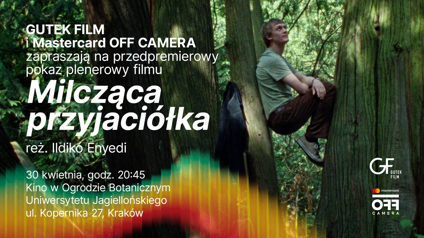 Mężczyzna siedzący na rozgałęzieniu dużego drzewa w zielonym lesie, w tle intensywna roślinność oraz napisy informujące o pokazie plenerowym filmu „Milcząca przyjaciółka” w Ogrodzie Botanicznym Uniwersytetu Jagiellońskiego.