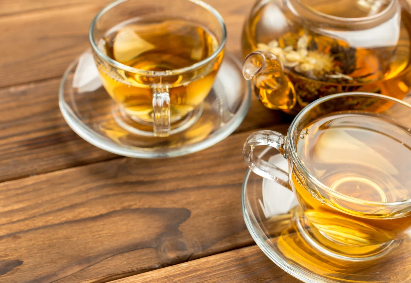 Napar z kwiatów tarniny chroni od pajączków na nogach, chorób serca i nerek Dwie filiżanki naparu z kwiatów tarniny i dzbanek na drewnianym stole, jasnobrązowy kolor herbaty.