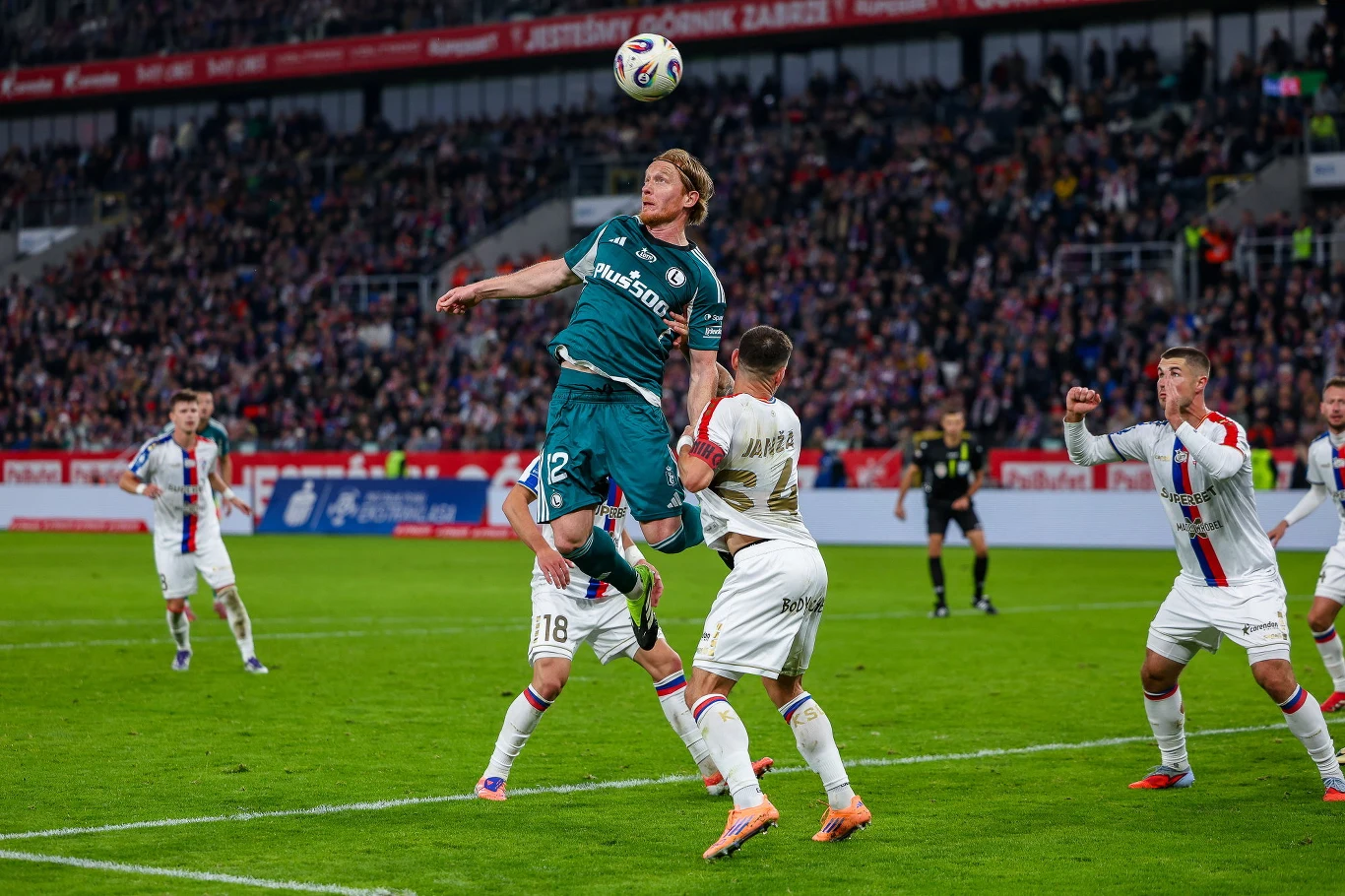 Radovan Pankov w walce z rywalami podczas meczu Górnik - Legia Radovan Pankov w niebieskiej koszulce wyskakuje do piłki głową w polu karnym otoczony przez rywali z Legii.
