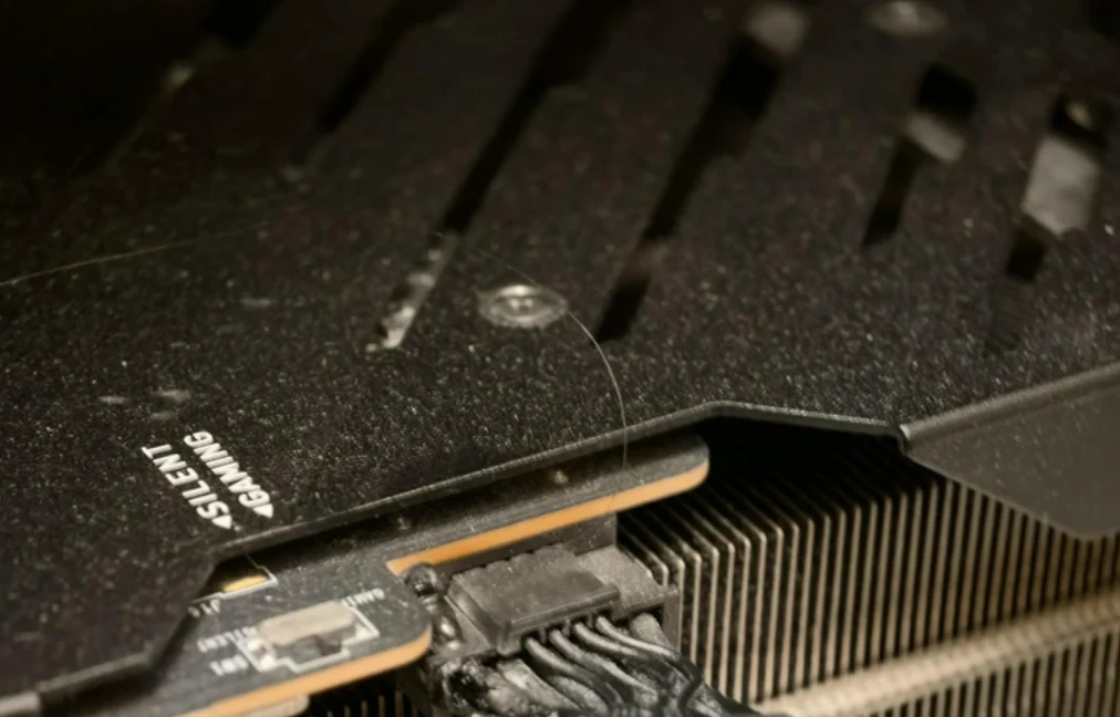 fragment karty graficznej z wyraźnie widocznym złączem zasilania oraz radiatorem chłodzącym, na czarnej obudowie widoczne logo SILENT GAMING