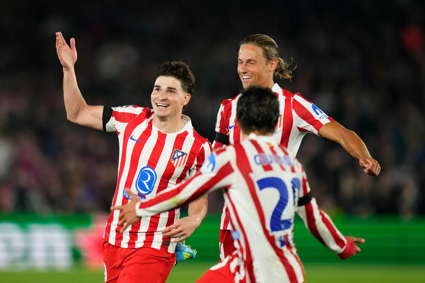 piłkarze drużyny Atletico Madryt w czerwono-białych koszulkach cieszą się po zdobytej bramce, uśmiechnięci i z wyciągniętymi rękoma wybiegają na murawę stadionu