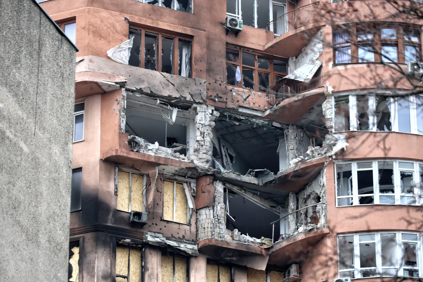 Wojna to największa z katastrof gospodarczych Zniszczona fasada budynku mieszkalnego z dużymi wyrwami i powybitymi oknami po eksplozji lub ostrzale.