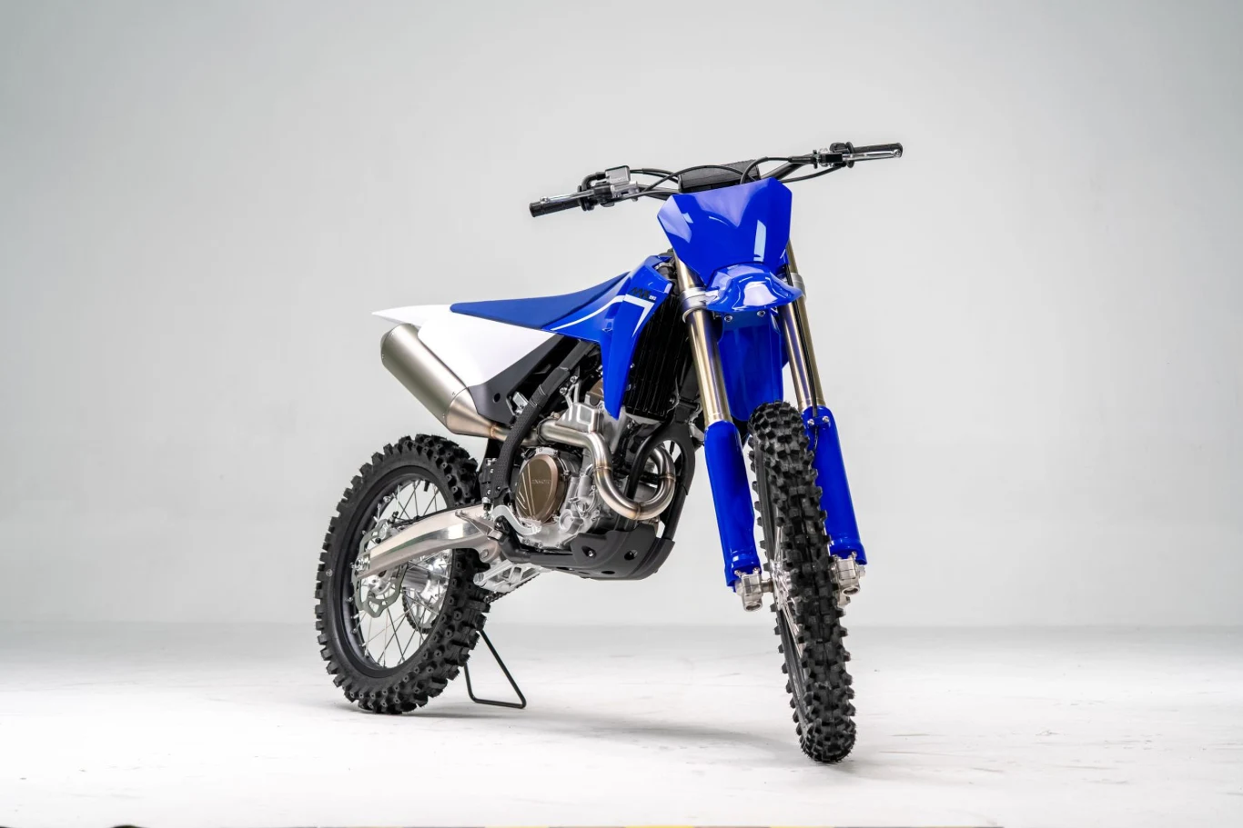 ZXMoto 250MX. motocykl crossowy w kolorze niebieskim z czarnymi kołami terenowymi, dużym wydechem po lewej stronie i masywnym zawieszeniem przednim na białym tle