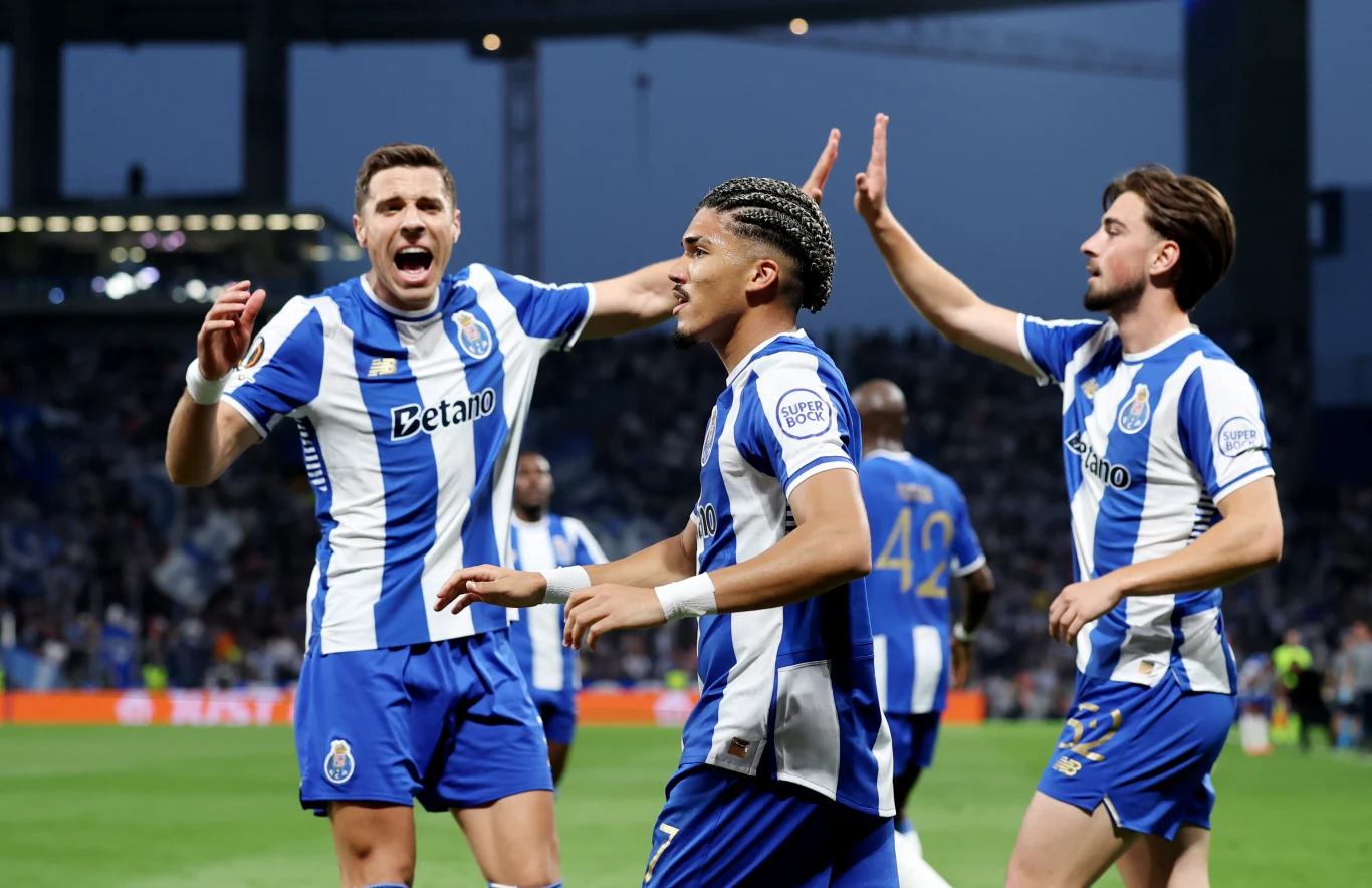 Piłkarze FC Porto w niebiesko-białych koszulkach świętują zdobycie gola na murawie stadionu, wykazując emocje i gesty radości w otoczeniu kibiców na trybunach.