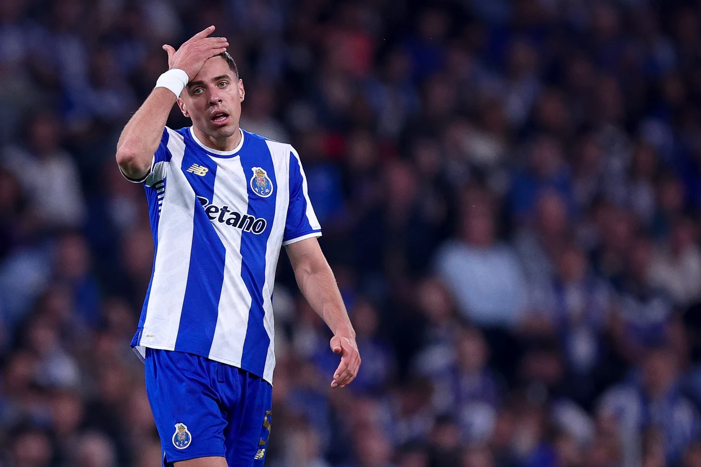 piłkarz w niebiesko-białej koszulce FC Porto z opaską kapitana dotyka czoła w geście zmartwienia podczas meczu na stadionie wypełnionym kibicami