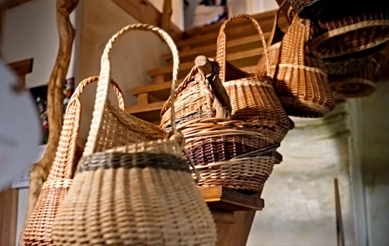 Kosze wyplatane w pracowni Macieja Pawlaka kosze wiklinowe o różnych kształtach i rozmiarach zawieszone w jasnym pomieszczeniu, w tle widoczne drewniane schody