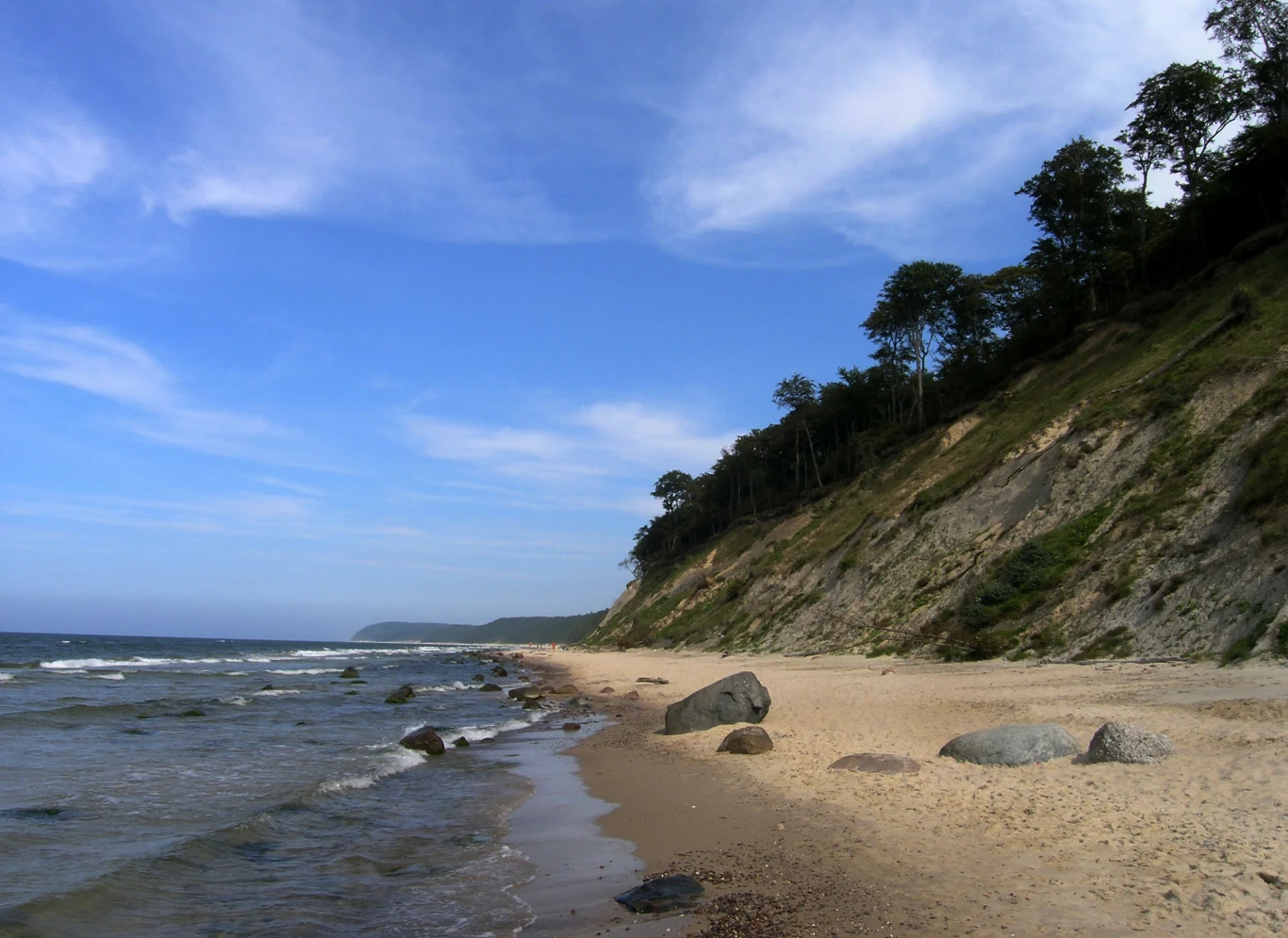 Na tej plaży odpoczniesz bez tłumów, nawet w środku sezonu. Zachwyca dzikością i spokojem. Piaszczysta plaża w Wisełce z dużymi głazami, stromym klifem i spokojnym morzem pod niebieskim niebem