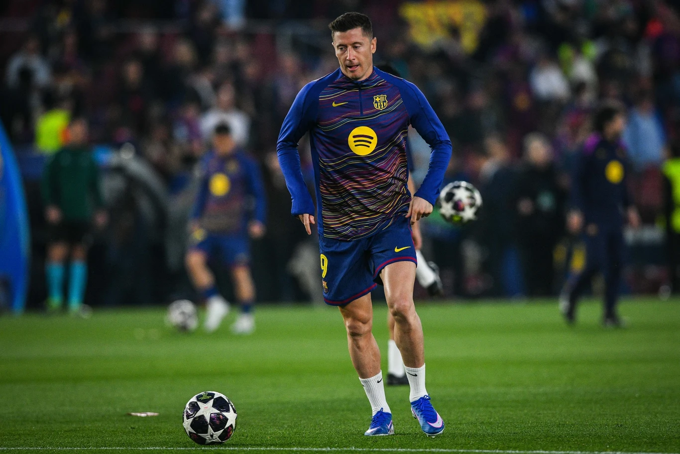 piłkarz w stroju treningowym FC Barcelony z piłką przy nodze podczas rozgrzewki na murawie stadionu