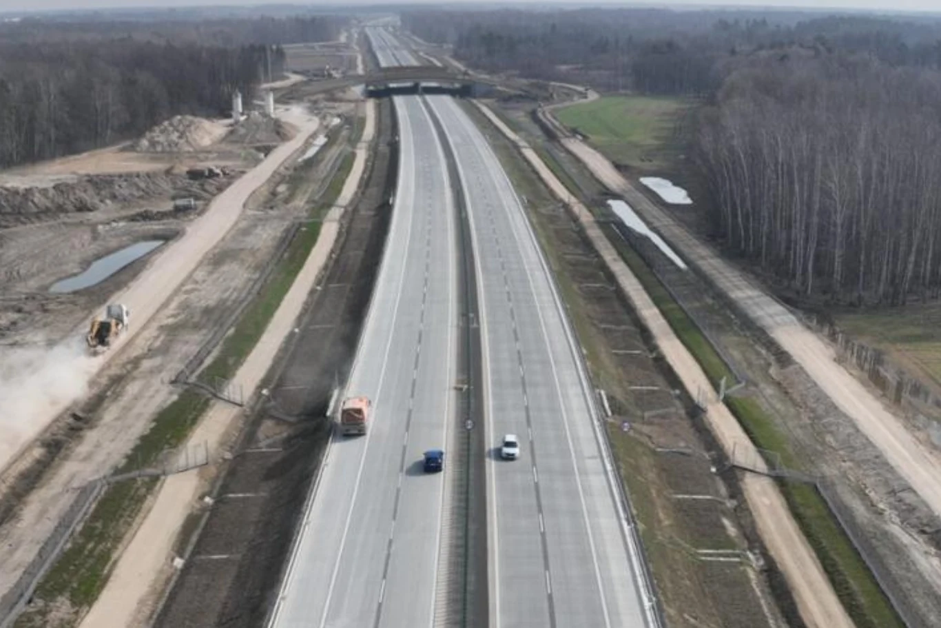 Do końca czerwca kierowcy przejadą nowym odcinkiem A2 o długości 65 km. Szeroka autostrada A2 z dwoma samochodami, pasy zieleni i prace ziemne po bokach trasy